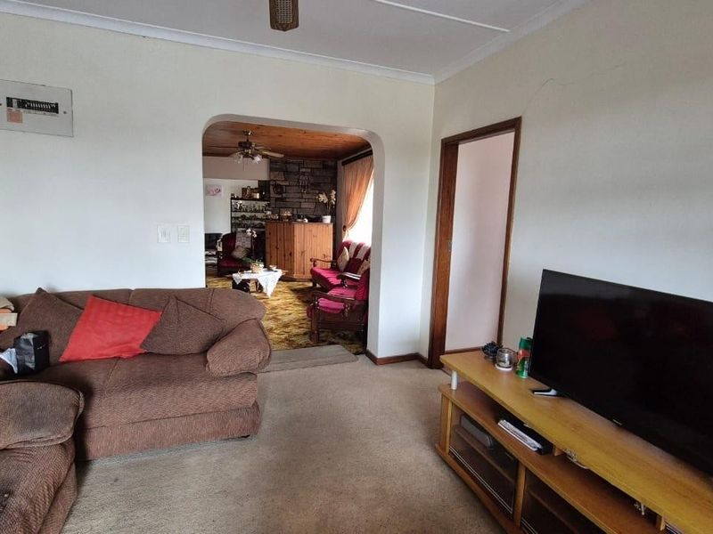 A living room featuring an arched doorway leading to an adjacent space, a ceiling fan, and a visible electrical distribution board on the wall.