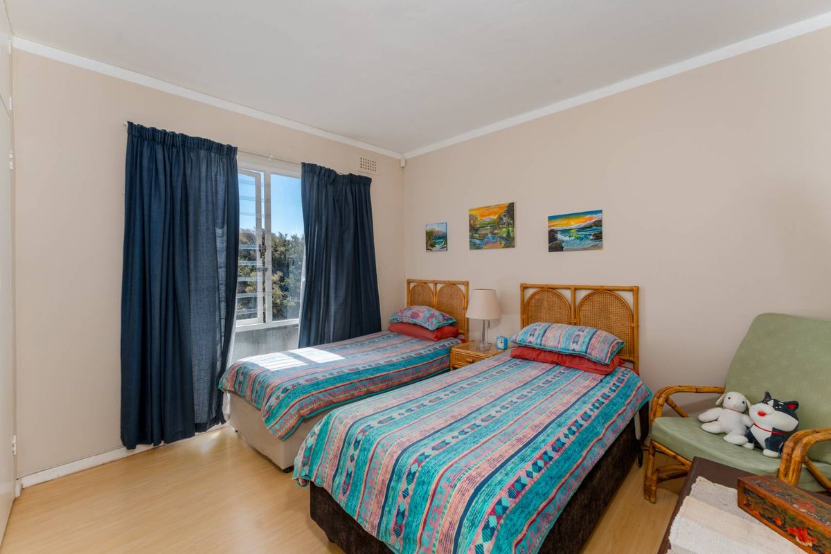 A well-lit bedroom featuring light wood-look flooring, neutral wall tones, and a window with natural light exposure.