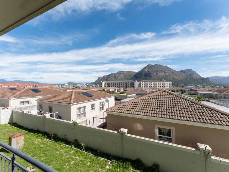 Elevated view overlooking a residential neighborhood with mountain scenery in the background, captured from an apartment balcony.