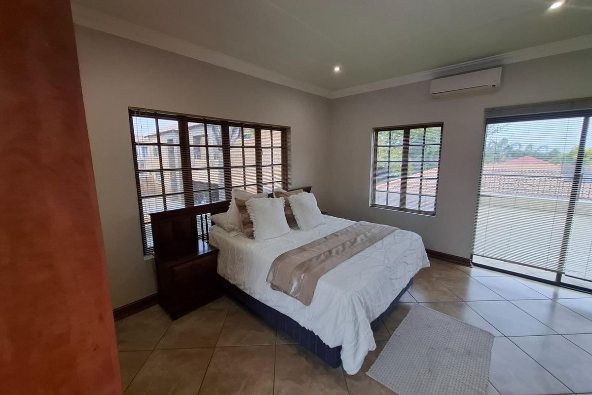 Spacious bedroom featuring tiled flooring, recessed downlighting, air conditioning, and large windows with fitted venetian blinds.