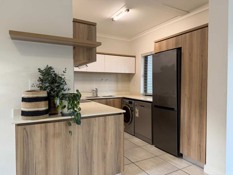 Modern kitchen featuring wood-look laminate cabinetry, stone countertops, tiled flooring, and integrated appliance spaces for a clean, functional layout.