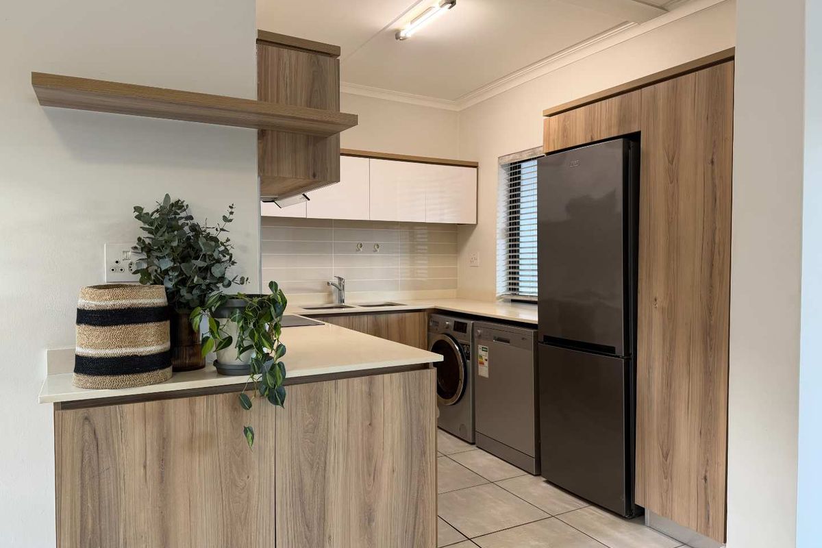 Modern kitchen featuring wood-look laminate cabinetry, stone countertops, tiled flooring, and integrated appliance spaces for a clean, functional layout.