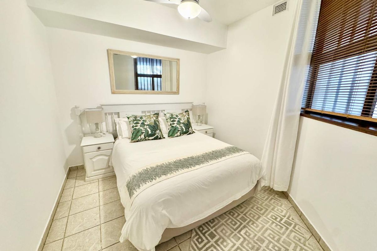 A compact bedroom featuring tiled flooring, a ceiling fan, and a window with fitted blinds.
