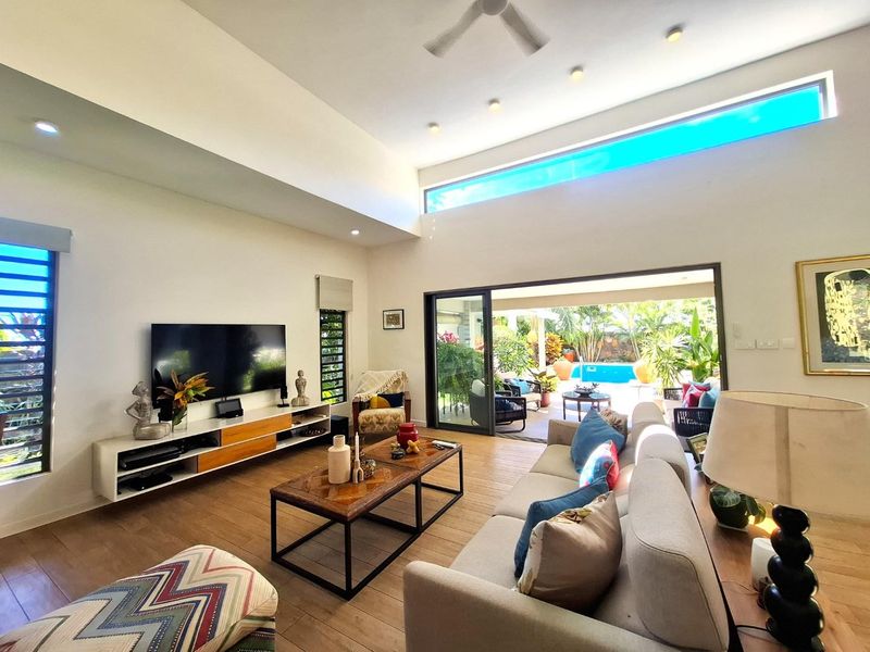Spacious living room with high ceilings, clerestory windows, and large sliding doors opening to a patio and pool area.