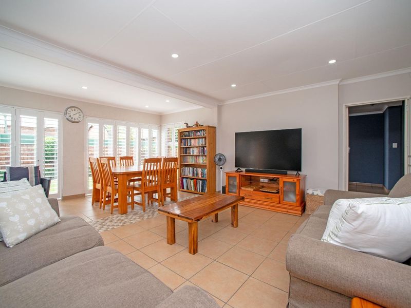 Spacious open-plan living and dining area featuring neutral tiled flooring, recessed lighting, and white plantation shutters providing ample natural light.