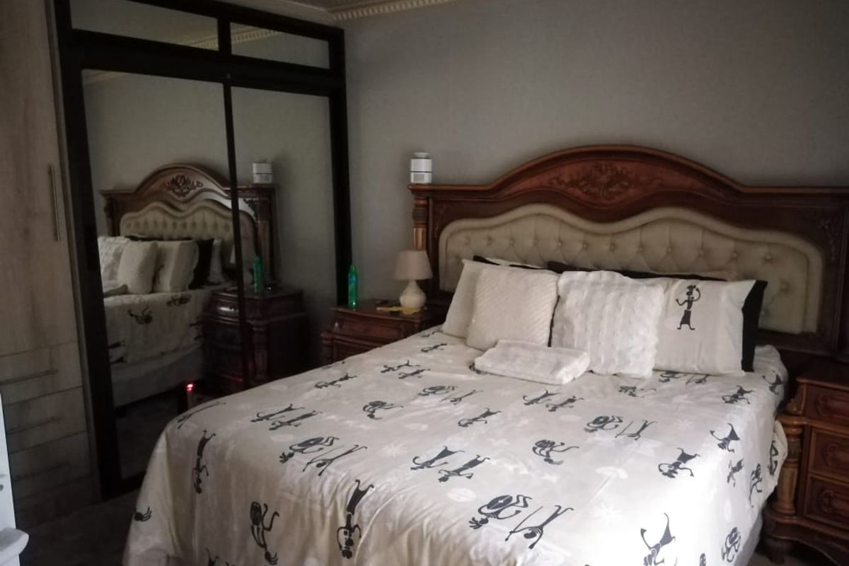 A bedroom featuring built-in mirrored sliding door wardrobes and decorative crown molding.