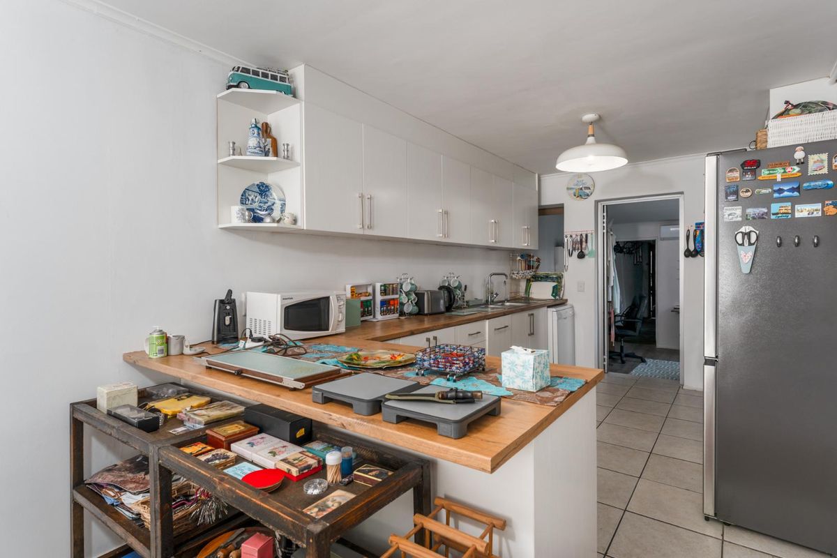 Functional kitchen featuring white cabinetry, wooden countertops, and tiled flooring, providing a practical workspace with direct access to adjacent rooms.