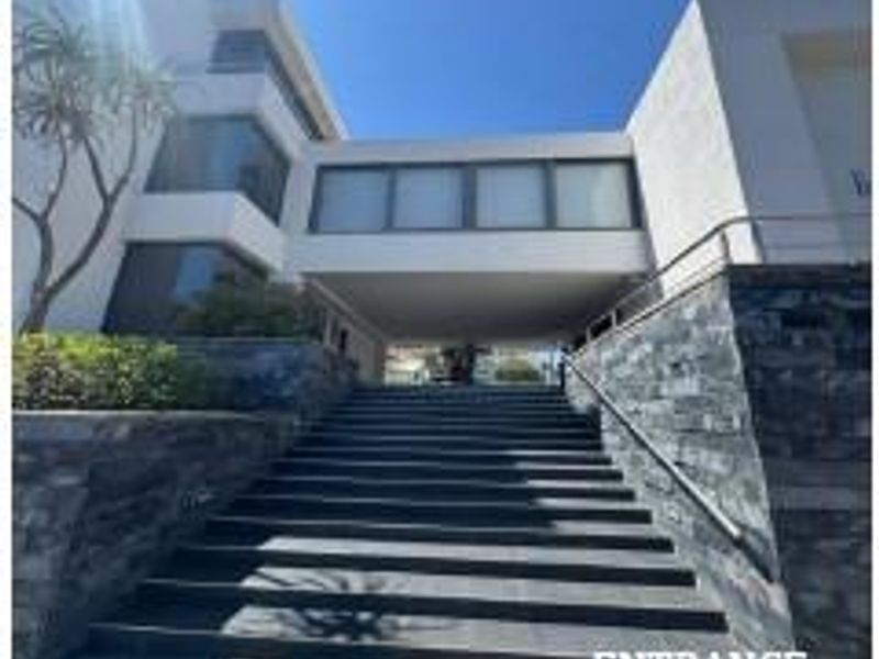 Modern office building entrance featuring a wide stone staircase, stone-clad retaining walls, and a contemporary architectural facade.