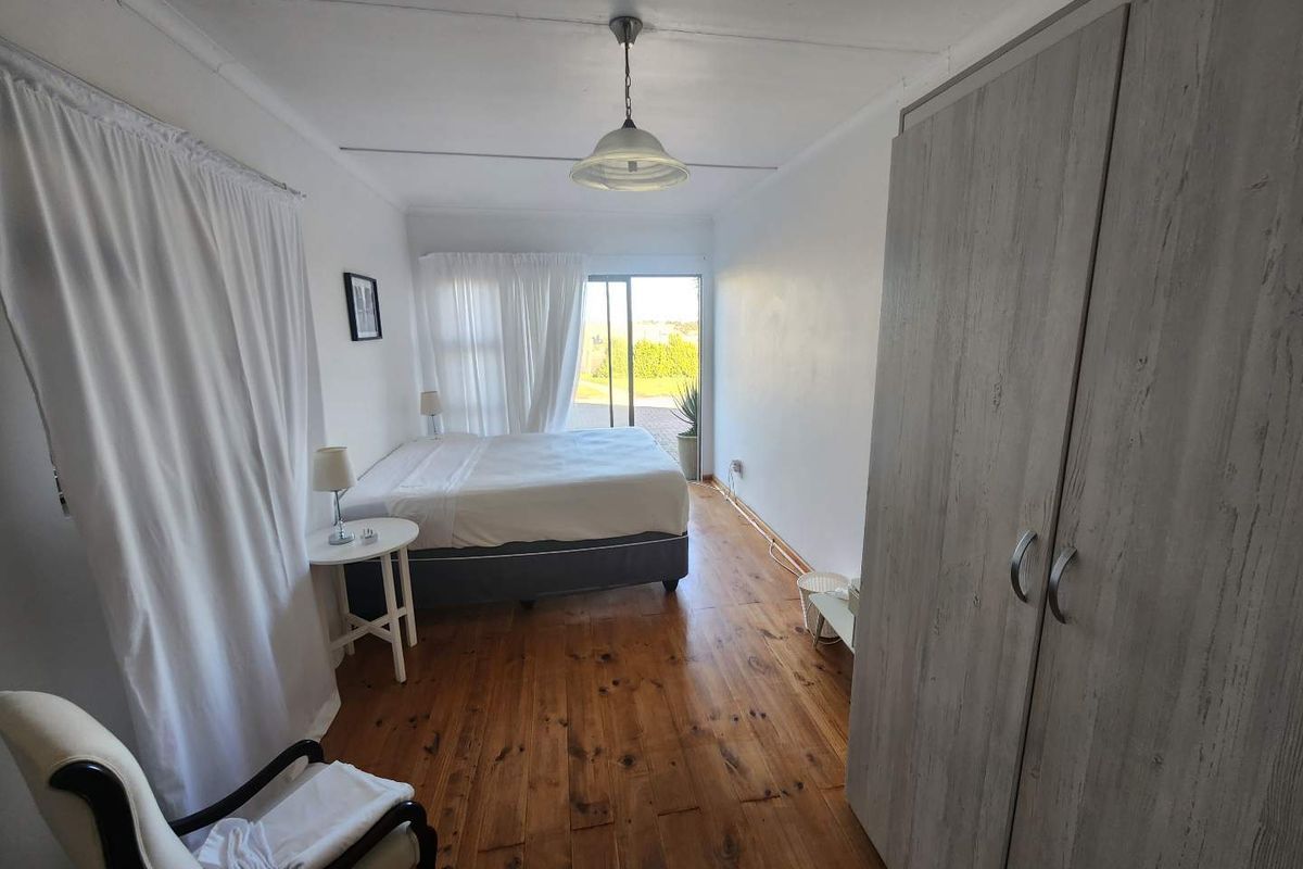 A bedroom featuring polished wooden flooring, built-in wardrobe, and sliding glass doors providing natural light and access to the outdoor area.