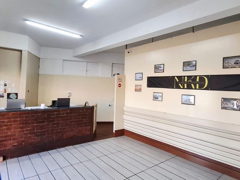 A functional business reception area featuring a brick-faced counter, tiled flooring, and bright overhead lighting, suitable for a professional office or service space.