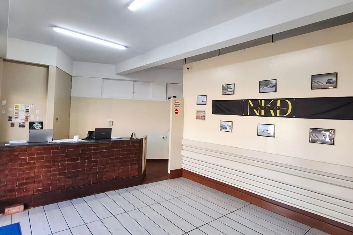 A functional business reception area featuring a brick-faced counter, tiled flooring, and bright overhead lighting, suitable for a professional office or service space.