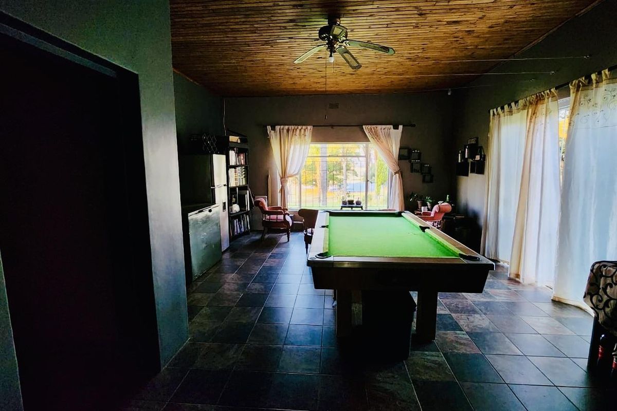 Spacious living area featuring dark slate tile flooring, a warm timber-clad ceiling, and large windows providing natural light and garden views.