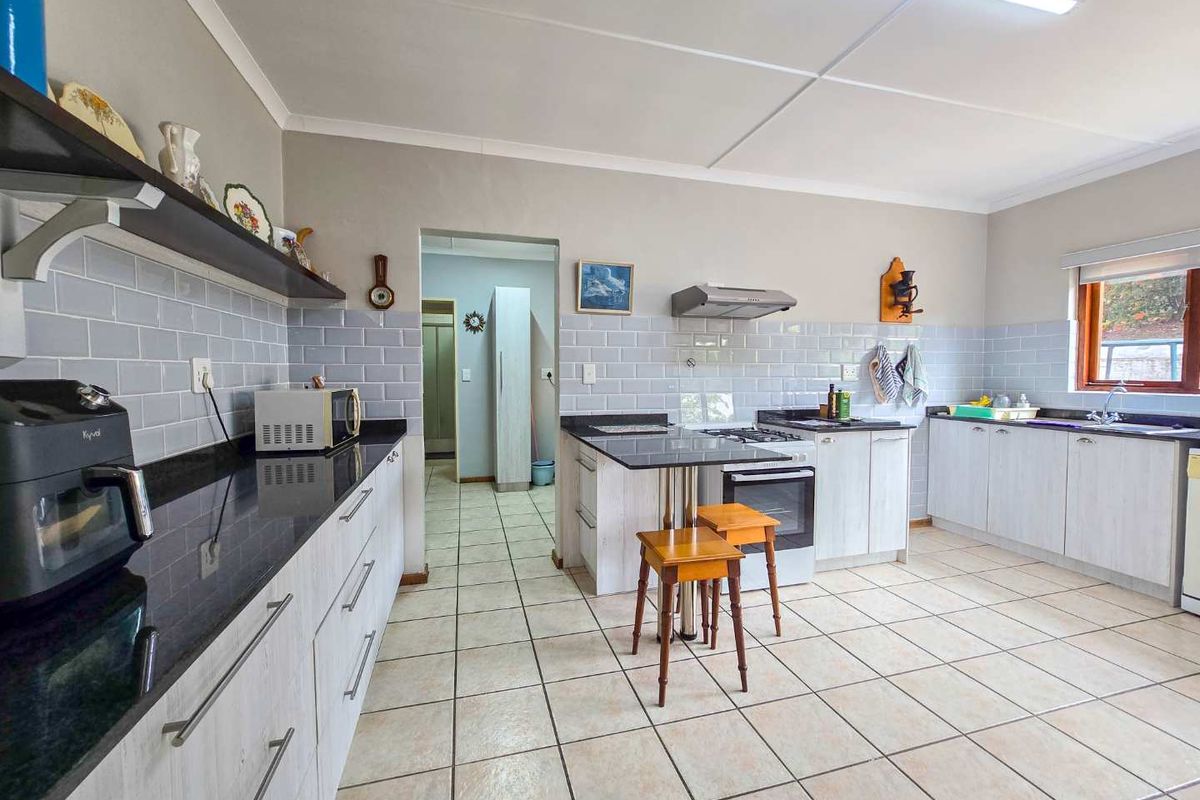 Spacious kitchen featuring light-toned cabinetry, dark granite countertops, subway tile backsplash, and a built-in stove with extractor fan.