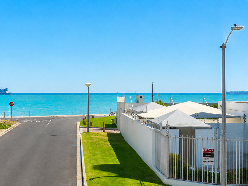 A clear view of the ocean and coastal road from the property, featuring well-maintained perimeter fencing and street infrastructure.