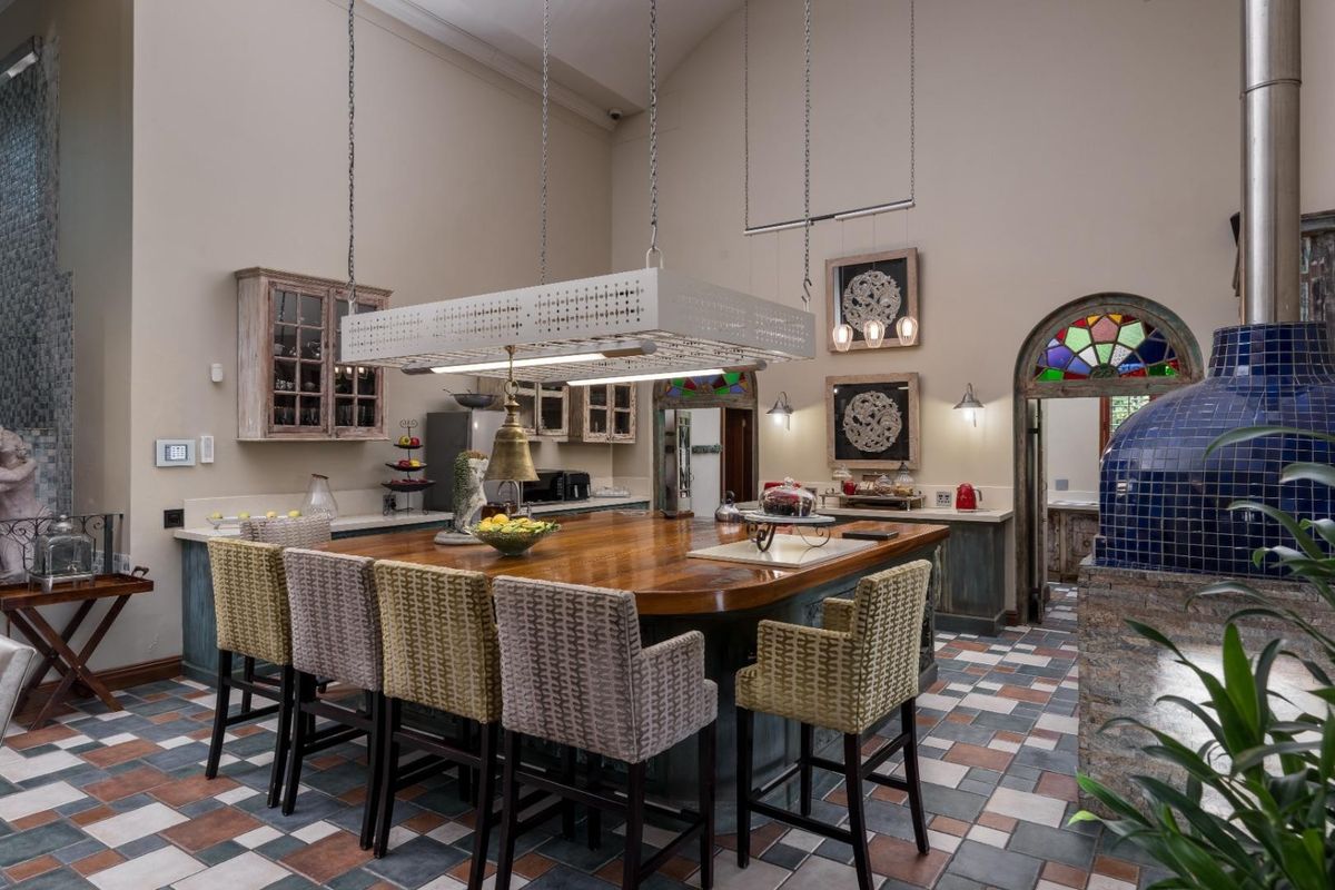 Spacious kitchen featuring a large central wooden island, vaulted ceilings, custom cabinetry, and a distinctive blue tiled pizza oven.