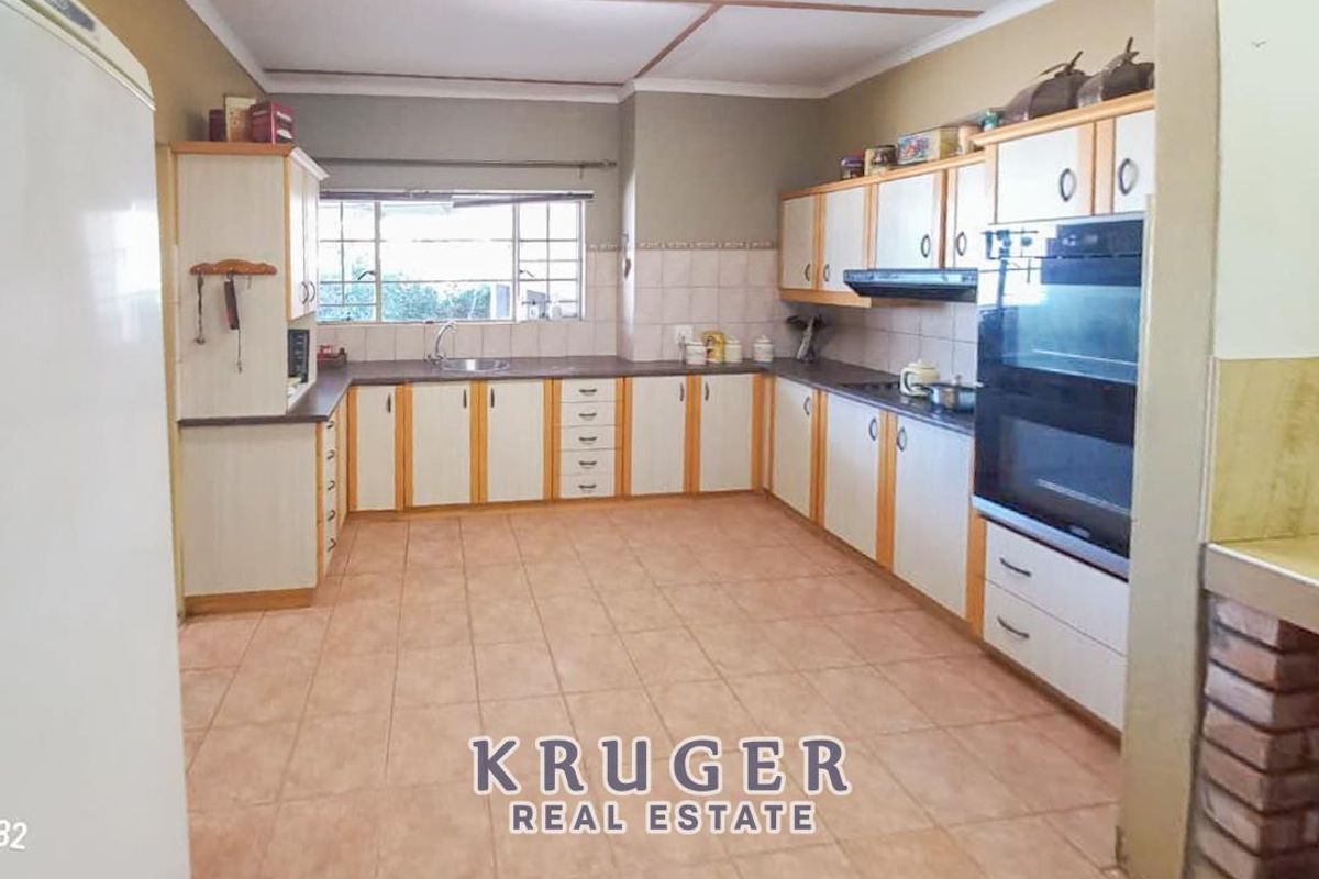 A functional kitchen featuring U-shaped cabinetry, built-in double oven, extractor fan, and tiled flooring with ample counter space.