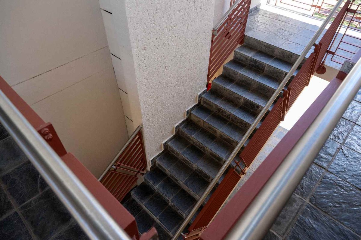 An elevated view of an outdoor staircase featuring tiled steps and metal railings, providing access between levels of the apartment complex.