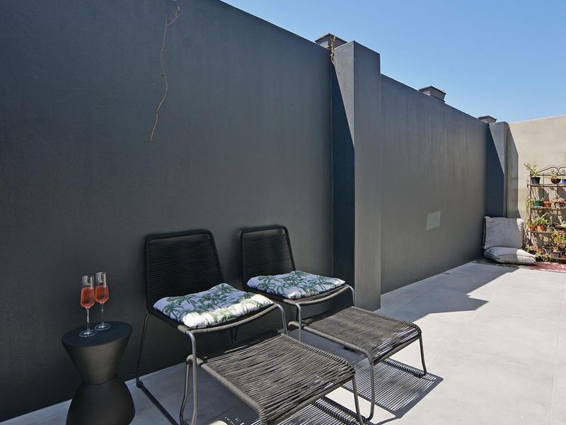 A private outdoor patio area featuring a high boundary wall and clean tiled flooring, perfect for relaxation.