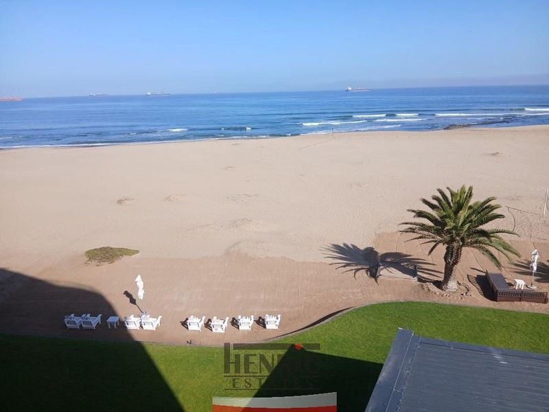 Elevated view overlooking the sandy beach and ocean, featuring a well-maintained lawn area.