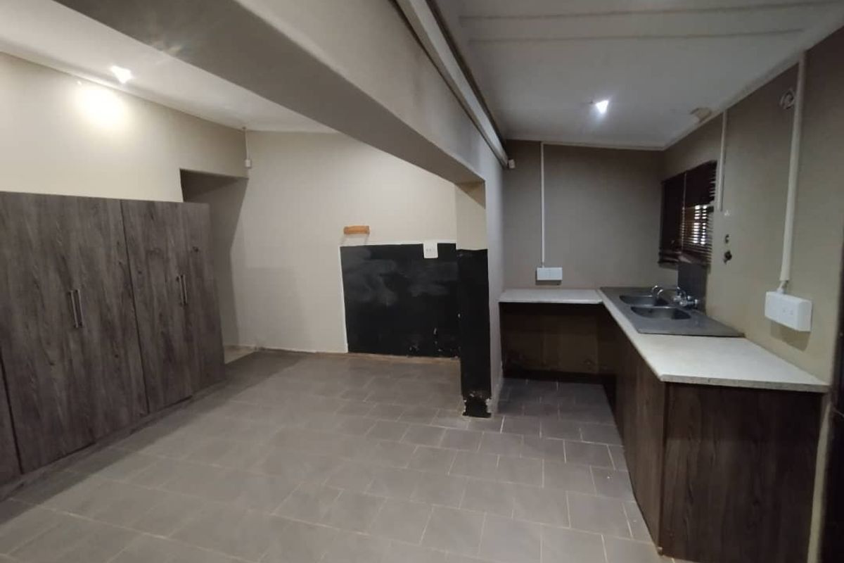 A functional kitchen space featuring built-in cabinetry, double sink, and tiled flooring, currently awaiting final finishes and cosmetic updates.
