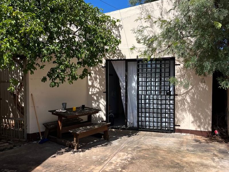 A paved outdoor patio area featuring a security gate and sliding glass door access to the main dwelling.