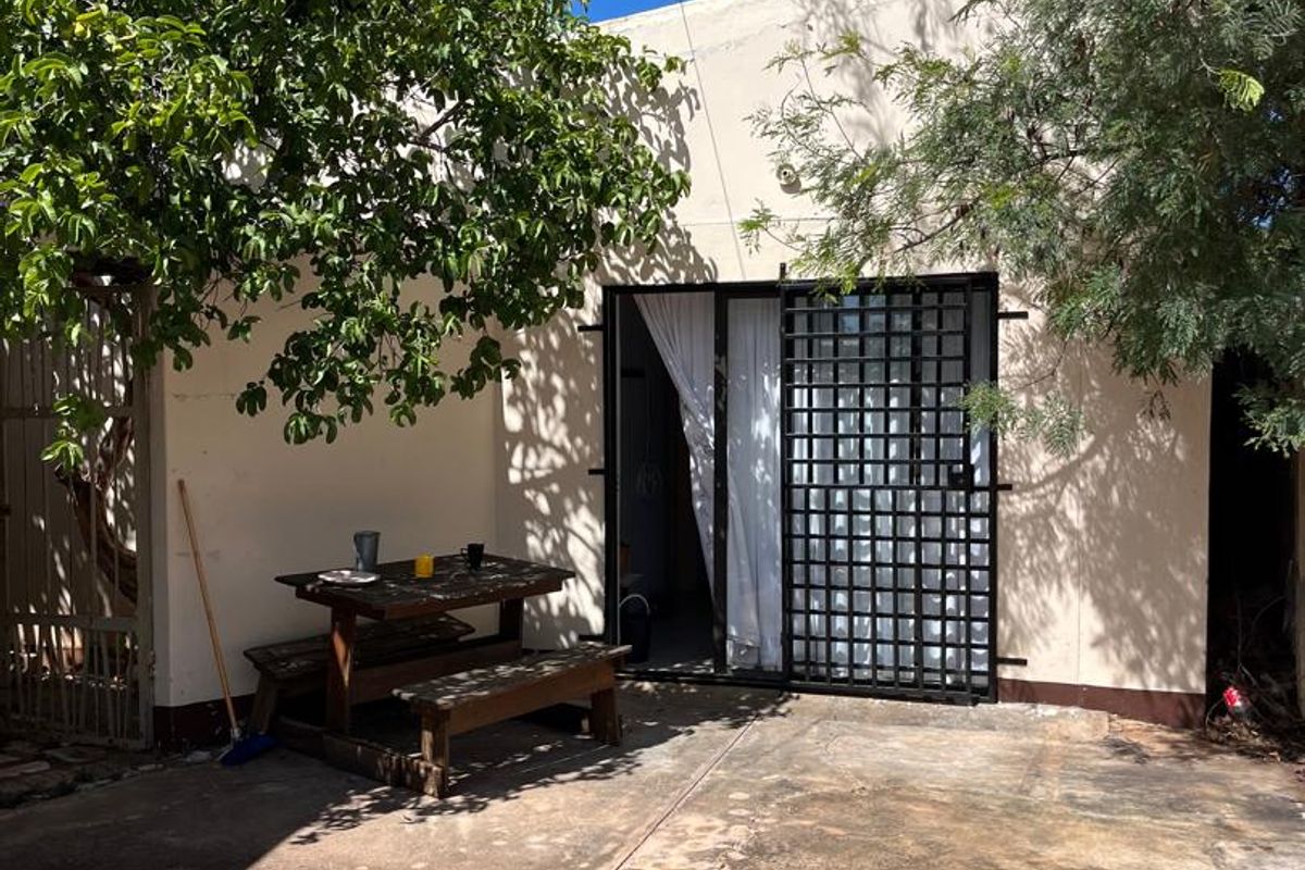 A paved outdoor patio area featuring a security gate and sliding glass door access to the main dwelling.