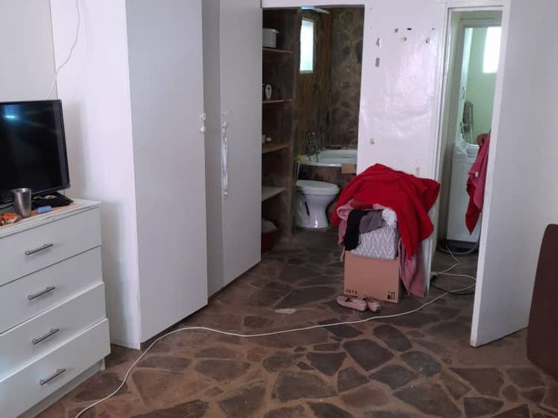 Bedroom featuring stone flooring and built-in wardrobe, with direct access to an en-suite bathroom. The room requires cosmetic updates to walls and finishes.