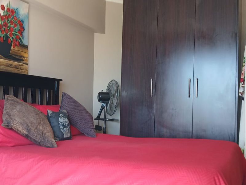 A bedroom featuring a dark wood built-in wardrobe and neutral wall finishes.