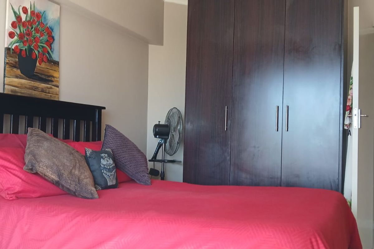 A bedroom featuring a dark wood built-in wardrobe and neutral wall finishes.