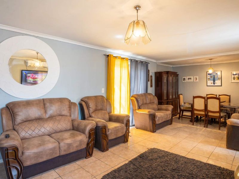An open-plan living and dining area featuring tiled flooring, neutral wall tones, and a sliding glass door providing access to the exterior.
