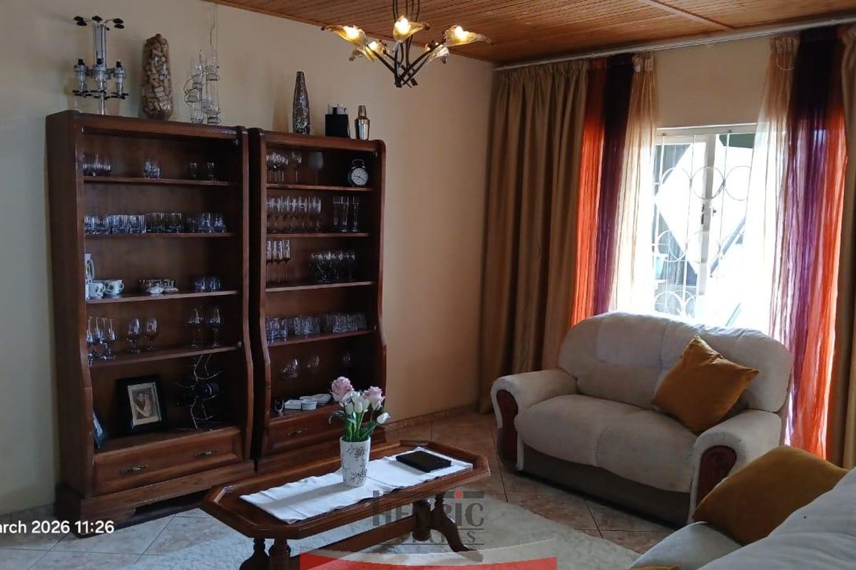 A living room featuring tiled flooring, a wooden ceiling, and a window with security bars.