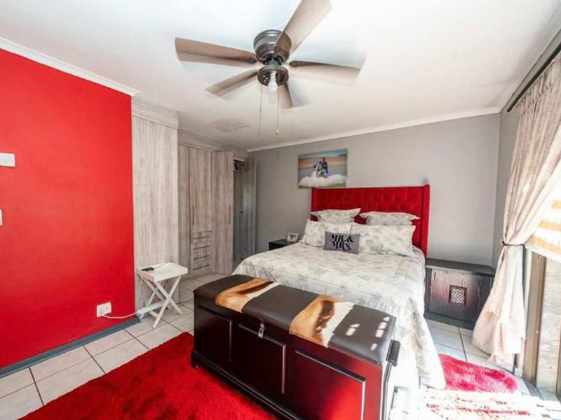 A bedroom featuring tiled flooring, built-in cupboards, and a ceiling fan, with access to an outdoor area via a sliding door.