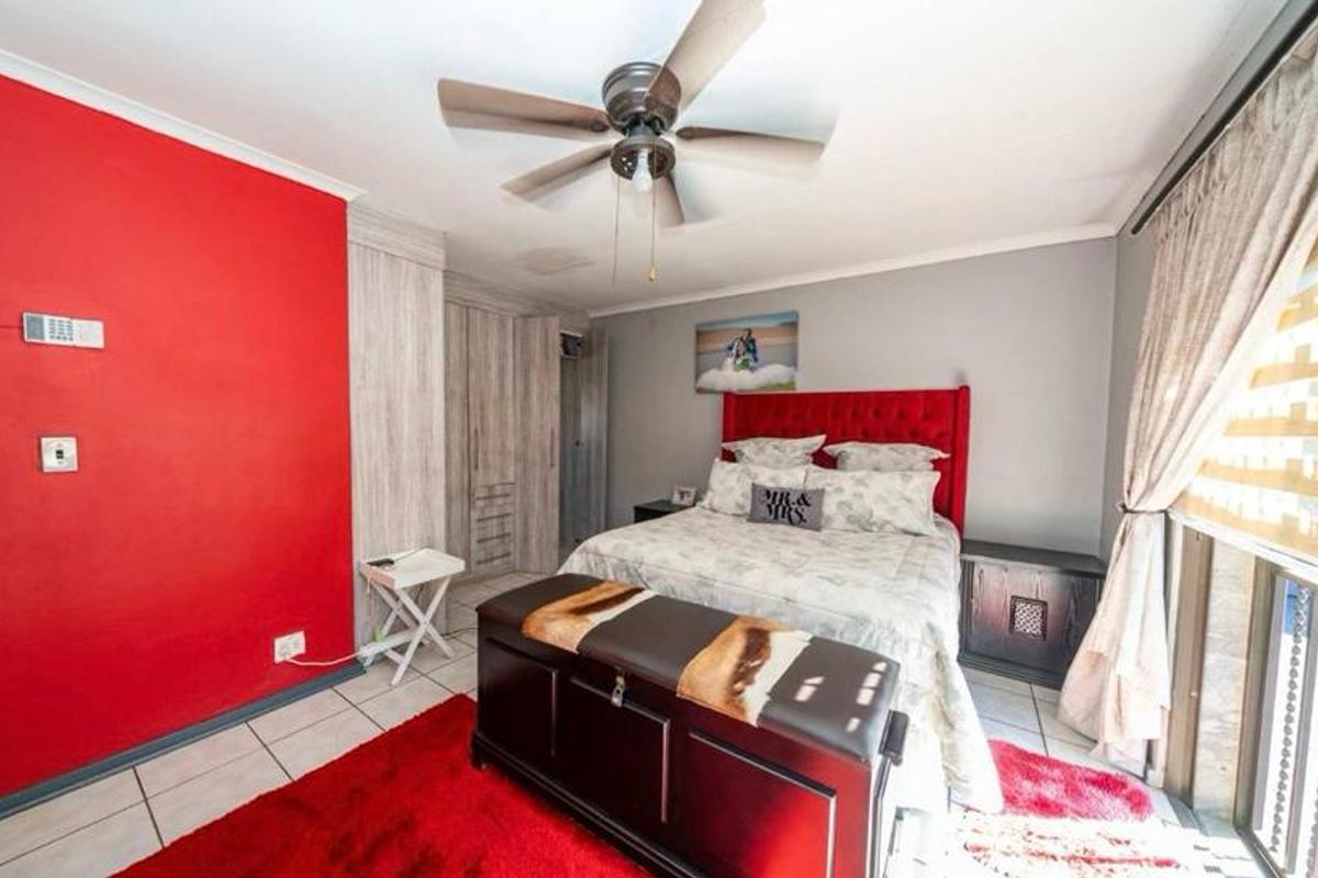 A bedroom featuring tiled flooring, built-in cupboards, and a ceiling fan, with access to an outdoor area via a sliding door.