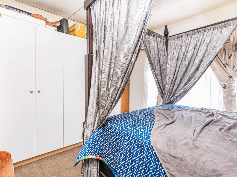 A bedroom featuring a built-in wardrobe and carpeted flooring, requiring some cosmetic updates to improve its overall condition.