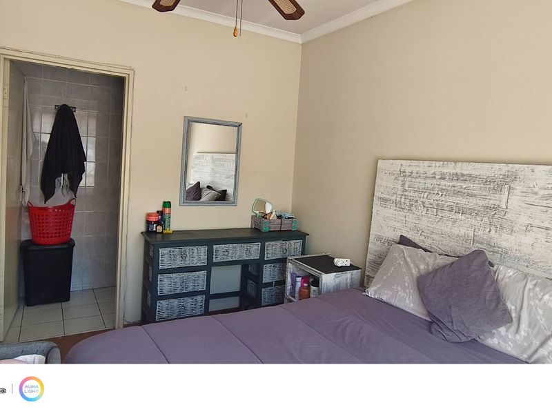 A bedroom featuring a ceiling fan, tiled flooring, and direct access to an en-suite bathroom.
