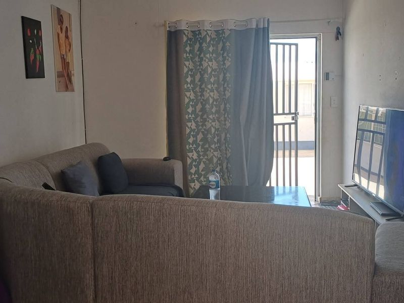 A living room area featuring a security gate and sliding door access to the exterior, with neutral wall finishes.