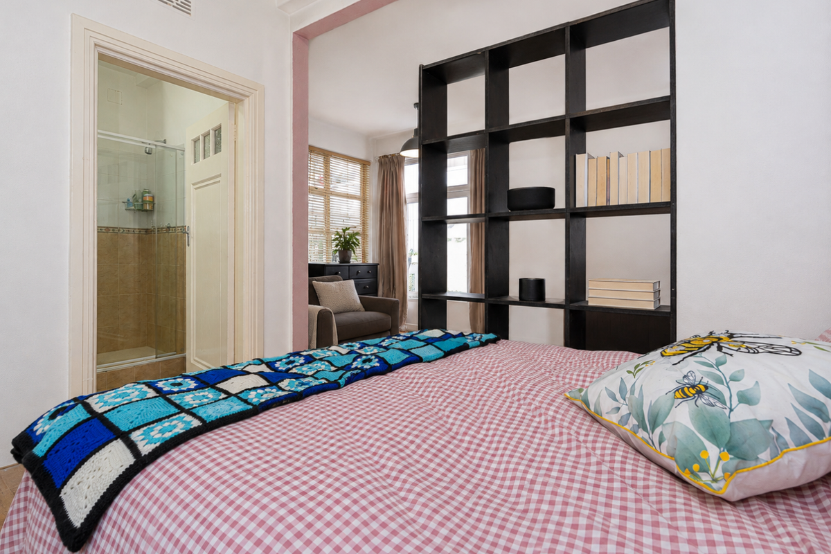 A bedroom featuring a built-in shelving unit and direct access to an en-suite bathroom with a shower enclosure.