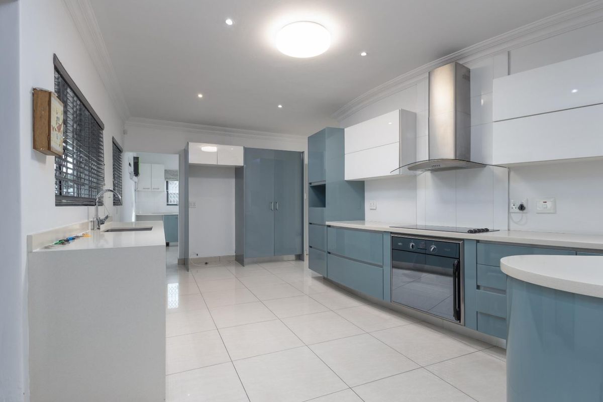 Modern kitchen featuring sleek blue and white cabinetry, stone countertops, integrated stainless steel appliances, and polished tiled flooring.
