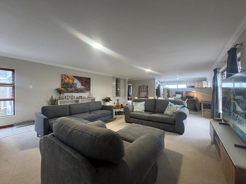 Spacious open-plan living area featuring neutral walls, recessed lighting, and a combination of carpet and tiled flooring, offering a versatile layout for family living.