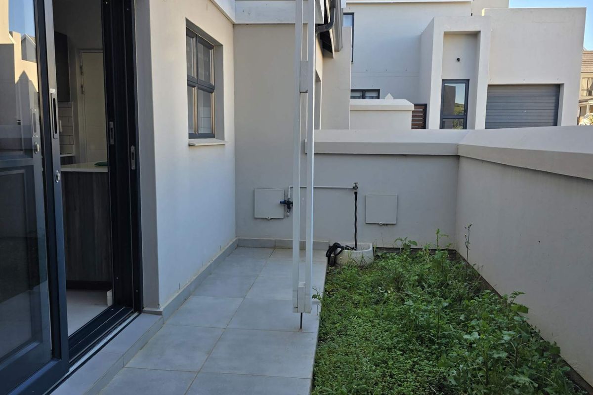 A private rear courtyard featuring tiled flooring, a small garden patch, and direct access to the interior through sliding glass doors.