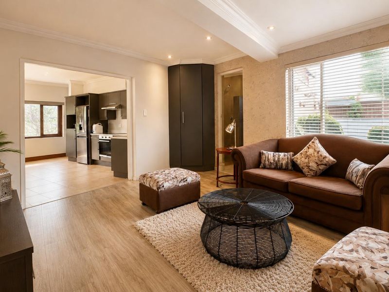 Open-plan living area featuring laminate flooring, crown molding, and recessed lighting, with a seamless transition into a modern kitchen space.