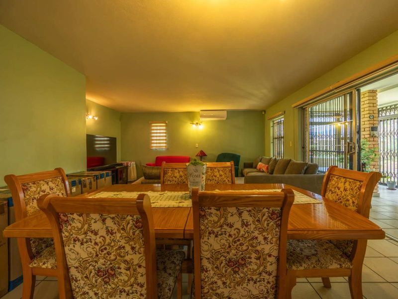 Spacious open-plan living and dining area featuring tiled flooring, split-system air conditioning, and large sliding glass doors leading to an outdoor patio.
