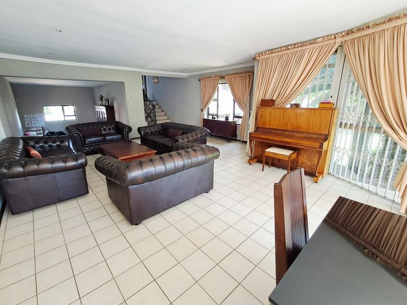 Spacious open-plan living area featuring neutral tiled flooring, recessed lighting, and large sliding doors providing access to the exterior.