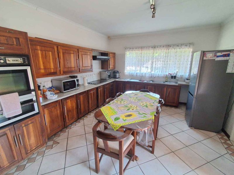Spacious kitchen featuring extensive wooden cabinetry, built-in oven, extractor fan, and tiled flooring, offering a functional layout with ample counter space.