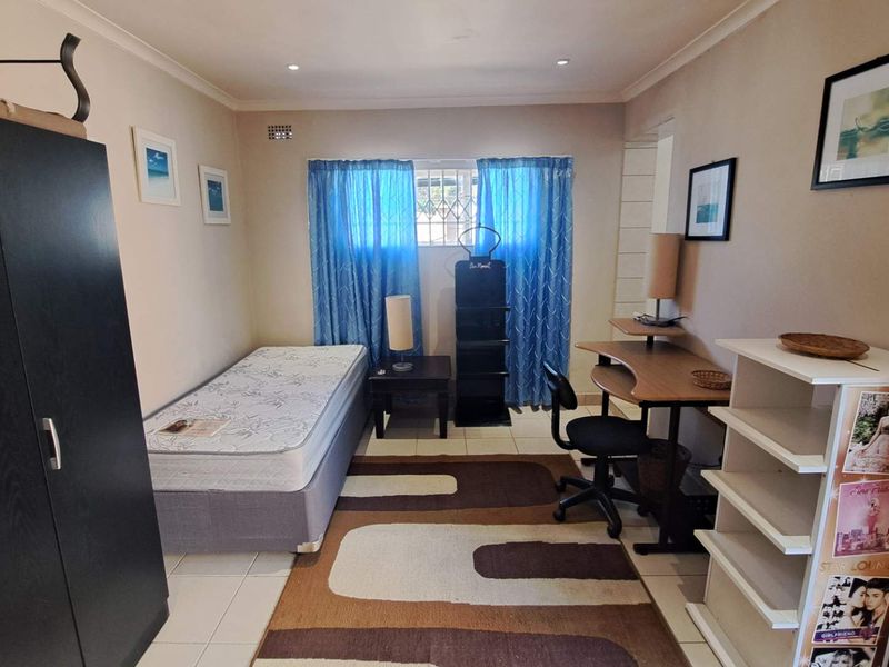 A functional bedroom featuring tiled flooring, recessed downlighting, and a security gate on the window.