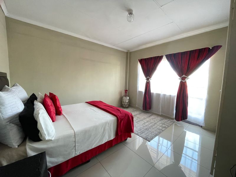 A bedroom featuring polished tiled flooring and ceiling cornice detailing, offering a neutral base ready for personalization.