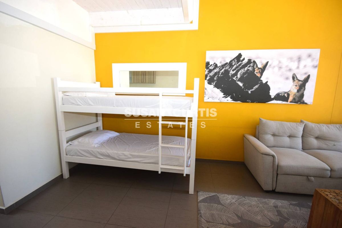 A bedroom featuring tiled flooring and an exposed beam ceiling, finished with a vibrant yellow accent wall.
