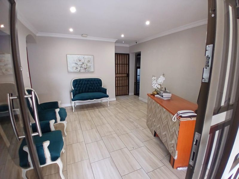 A bright and welcoming reception or entry area featuring neutral walls, tiled flooring, and recessed downlighting.