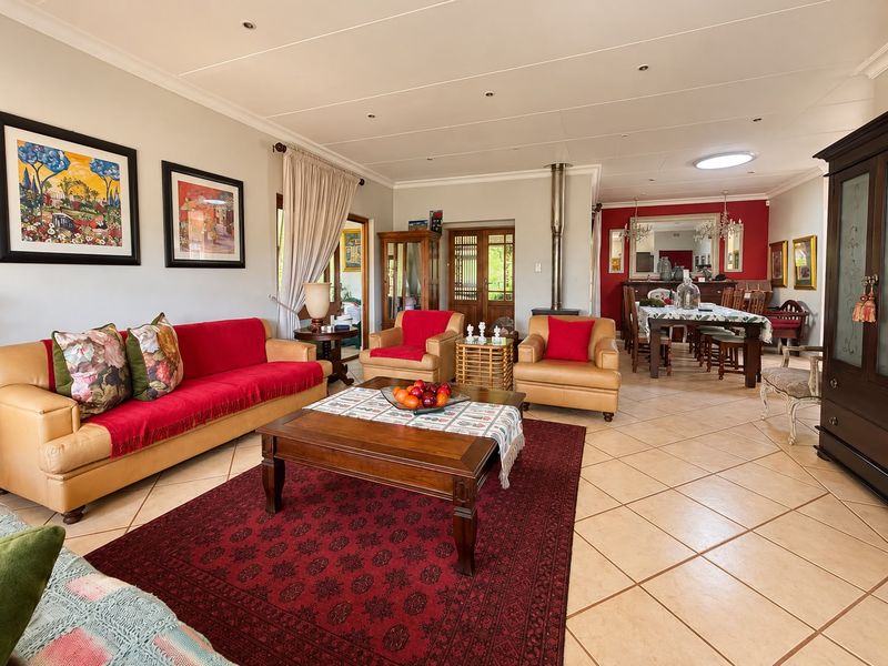 Spacious open-plan living and dining area featuring tiled flooring, a central fireplace, and natural light from a skylight and large windows.