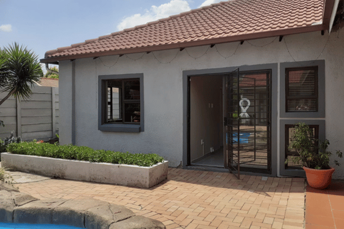 Rear exterior view of the cottage featuring a paved patio area, built-in planter box, and direct access to the swimming pool.